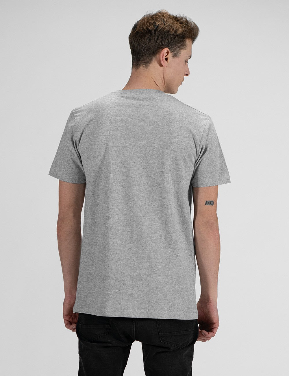 This image shows rear pose a man wearing a casual grey crew-neck t-shirt, and dark denim jeans.
