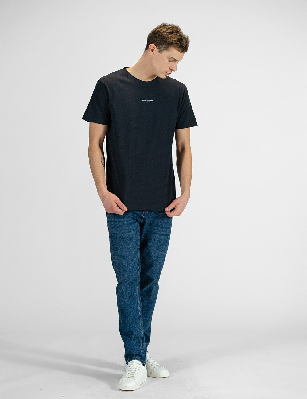 Man showcasing a navy round-neck T-shirt with the words “Rocket Scientist” on the front.