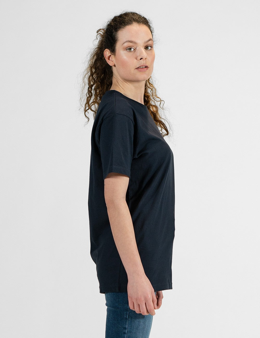 This image shows a young woman side pose, wearing a basic navy blue short-sleeve crewneck t-shirt.