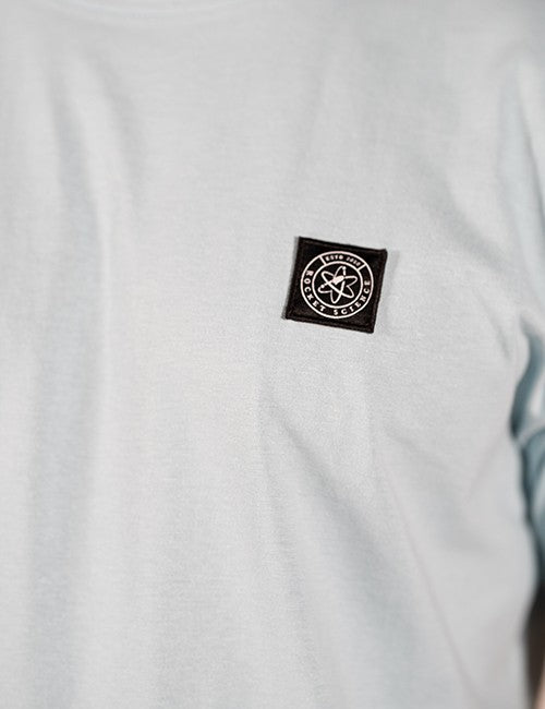 Close-up of a white  t-shirt featuring a black square patch on the left chest with the circular Rocket Science logo.