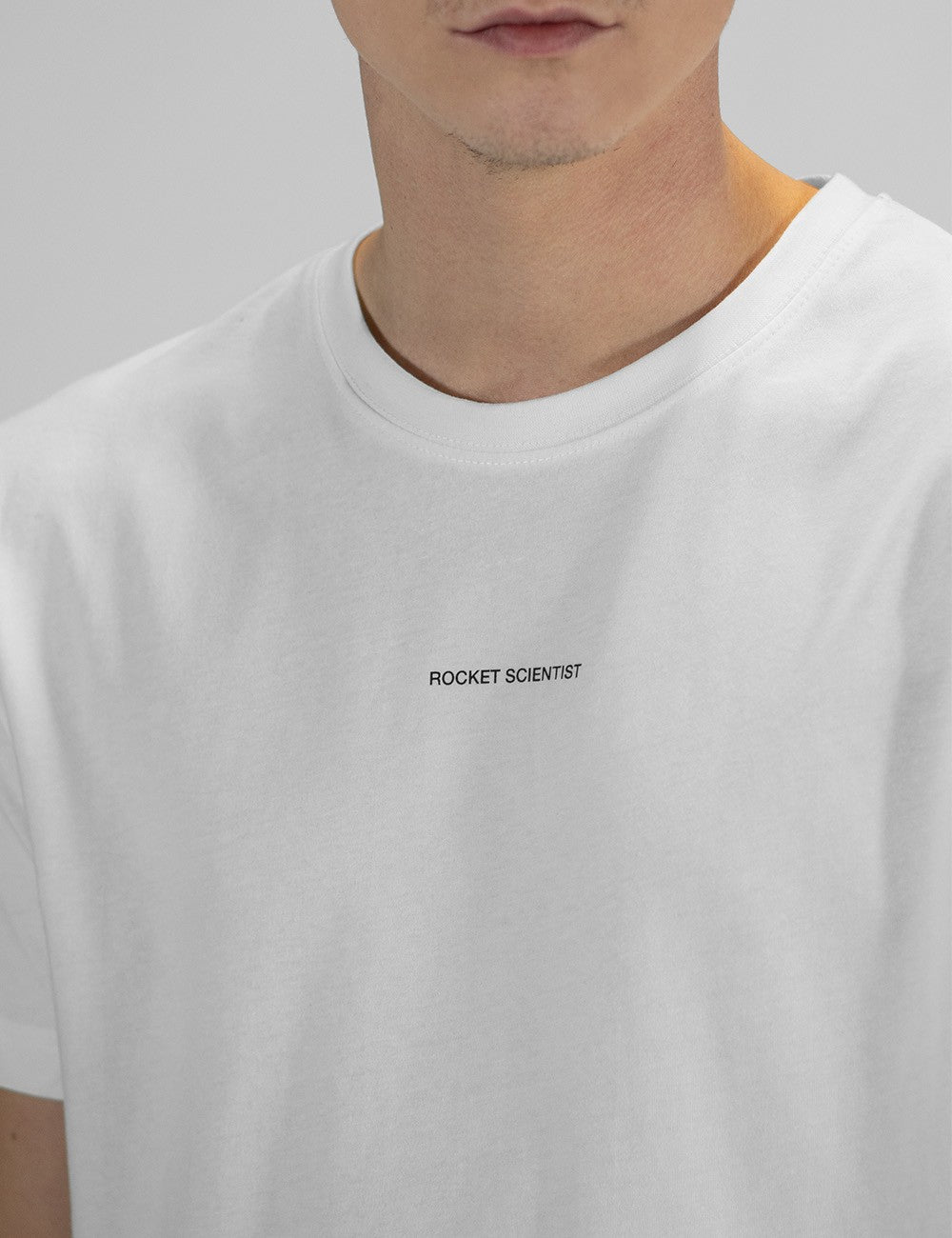 The image shows a white crew-neck T-shirt with a small "Rocket Scientist" text print on the chest.