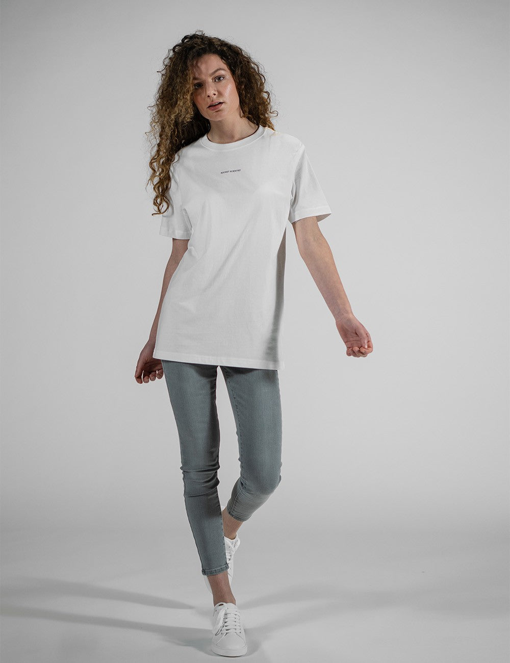 This image shows a woman wearing a casual white short-sleeved t-shirt featuring a subtle small "Rocket Scientist" print on the chest.