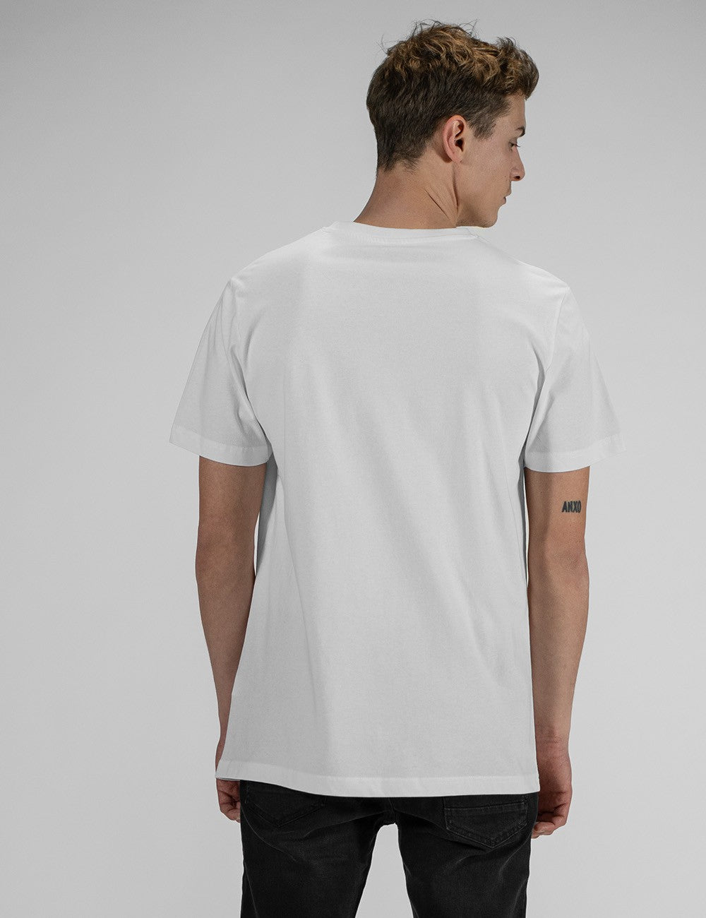 Rear view of a man with short brown hair wearing a plain white, short-sleeved crew neck t-shirt.
